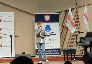 Chłopiec śpiewa na scenie.