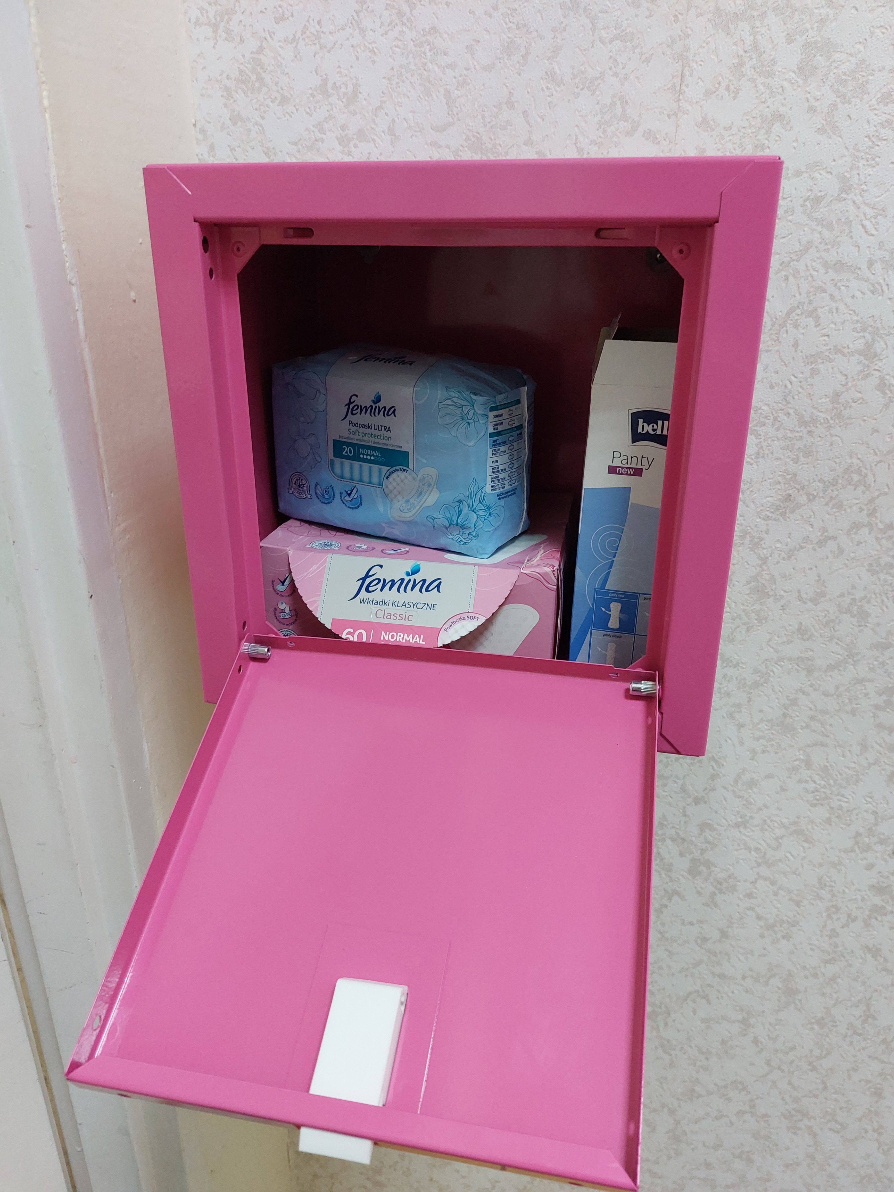 Akcesoria higieniczne dla dziewcząt umieszczone w różowej skrzynce.