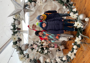 3 chłopców i Święty Mikołaj stoją w środku ozdoby w dużej kształcie bombki