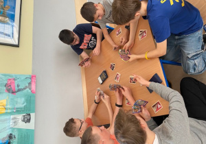 Grupa chłopców siedzi przy stole i gra w grę.