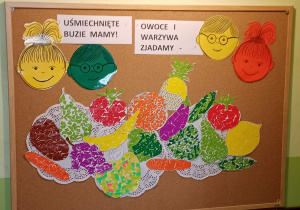 Wystawa prac plastycznych wykonanych przez uczniów klasy 1 d przedstawia owoce i warzywa na talerzach, na górze uśmiechnięte buzie dzieci