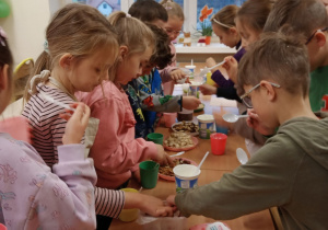Dzieci z klasy 1d przy ławkach przygotowują zdrowe jogurty