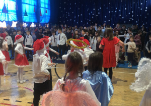 Dzieci tańczą na scenie. W tle widownia, która włącza się do tańca.