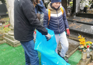 Dzieci sprzątają groby.