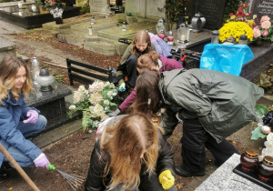 Dzieci sprzątają groby.