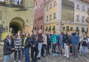 Uczniowie z klas siódmych i ósmych stoją na rynku w Poznaniu w tle kolorowe kamienice.